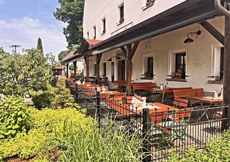 Biergarten an der Hauswand mit Blumen und Bänken