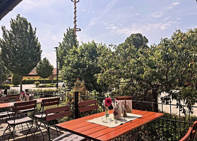 Gedeckter Tisch auf der Terrasse mit Blick ins Grüne und auf den Maibaum