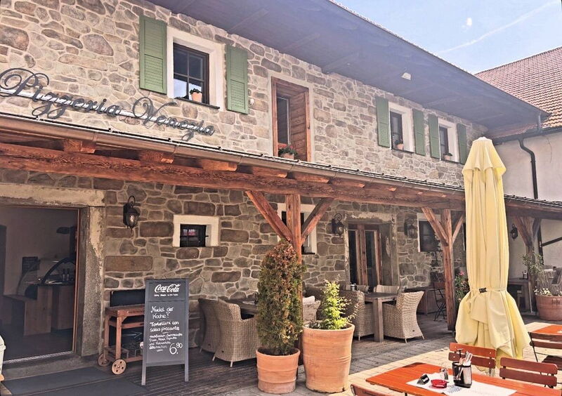 Eingang der Pizzeria Venezia mit Schriftzug und Sitzplätzen im Hof