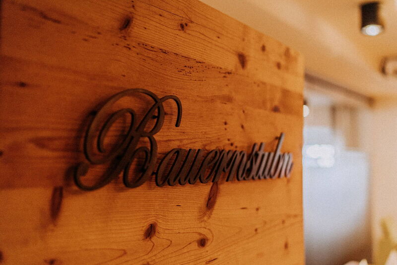 Holzschild „Bauernstubn“ an der Holzwand