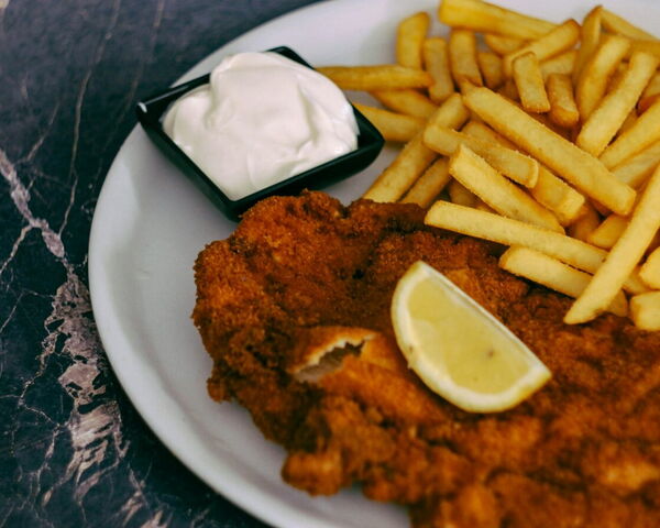 Paniertes Schnitzel mit Pommes frites, Zitronenspalte und Dip