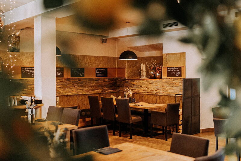 Blick durch Pflanzen in den Gastraum der Pizzeria