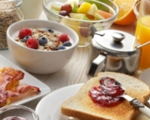 Frühstück mit Rührei, Speck, Müsli, Obst und Orangensaft