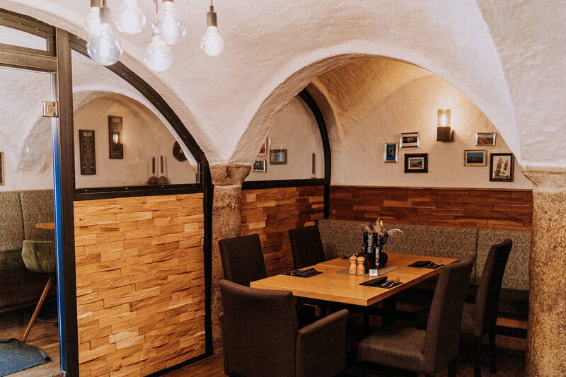 Gewölberaum mit Holztisch und Bilderwand