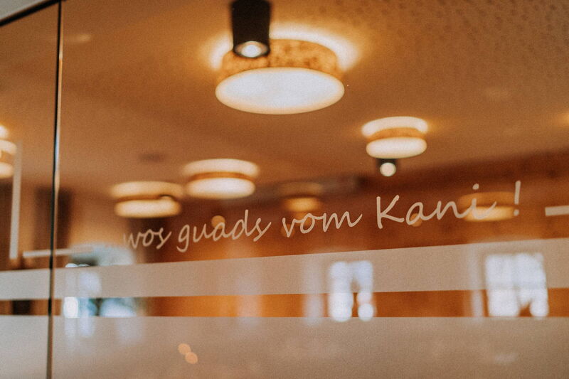 Glastür mit dem Schriftzug „wos guads vom Kani“