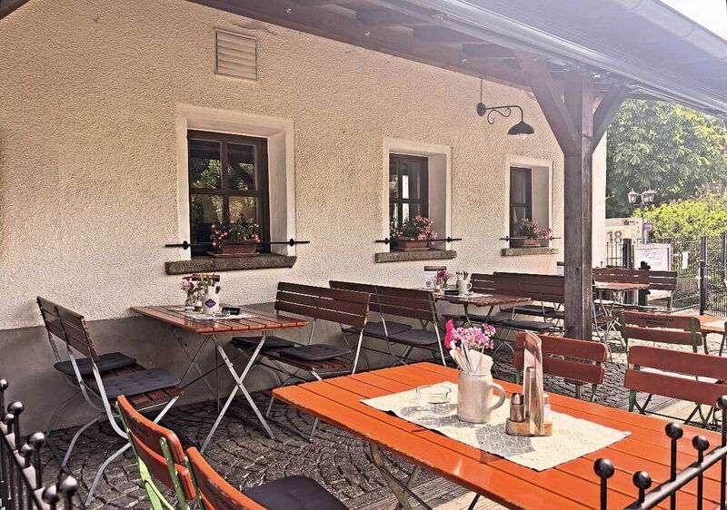 Biergarten unter dem Vordach mit gedeckten Tischen